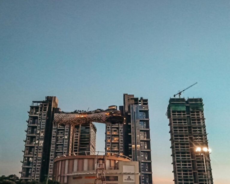 Contemporary highrise buildings with a unique connector, captured during twilight.